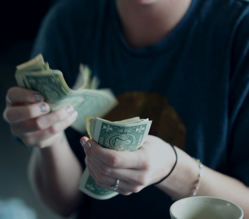 focus photography of person counting dollar banknotes