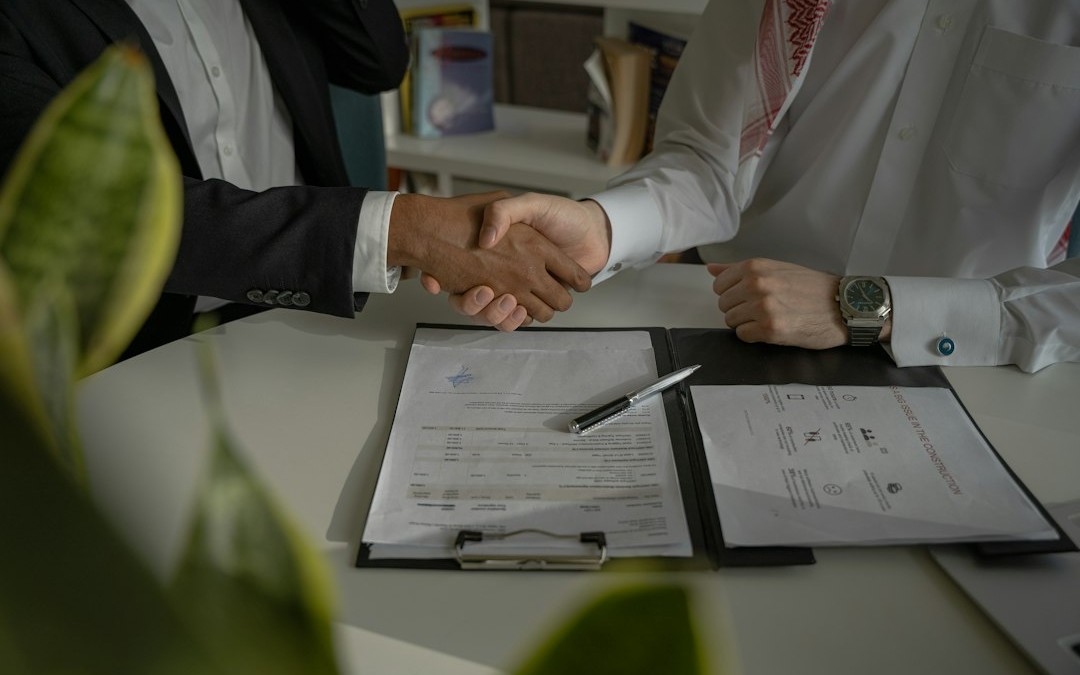 two people shaking hands over a piece of paper